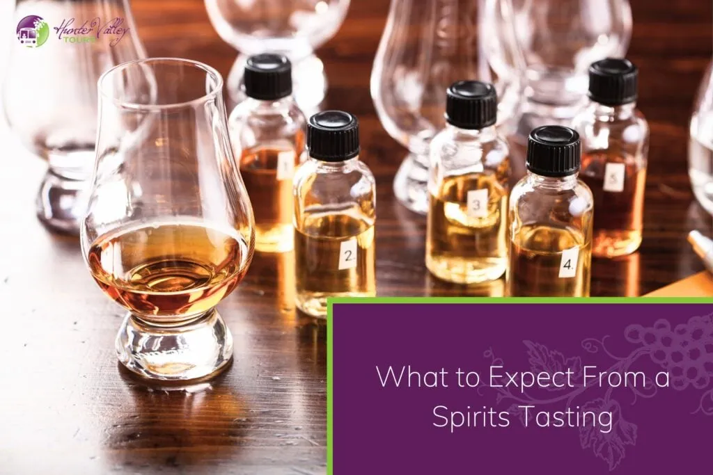 Several small numbered glass bottles filled with amber-coloured spirits arranged alongside tasting glasses on a wooden table.