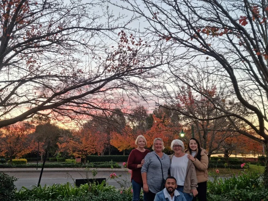 A tour group in front of autumn foliage at sunset