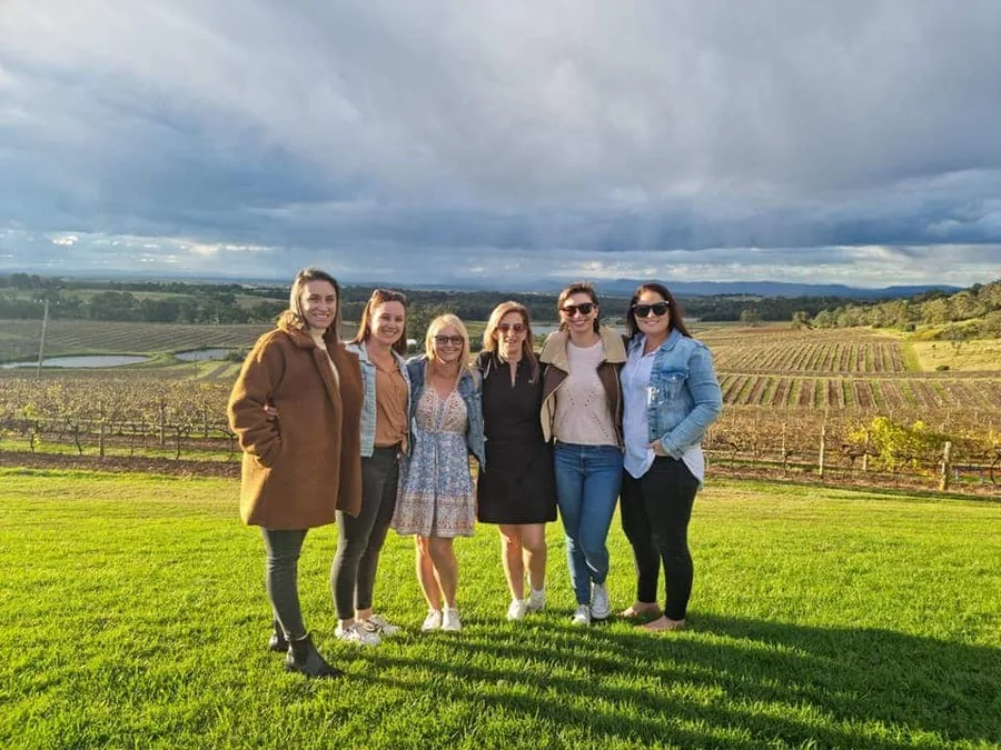 A group of friends laughing together in a Hunter Valley paddock between stops