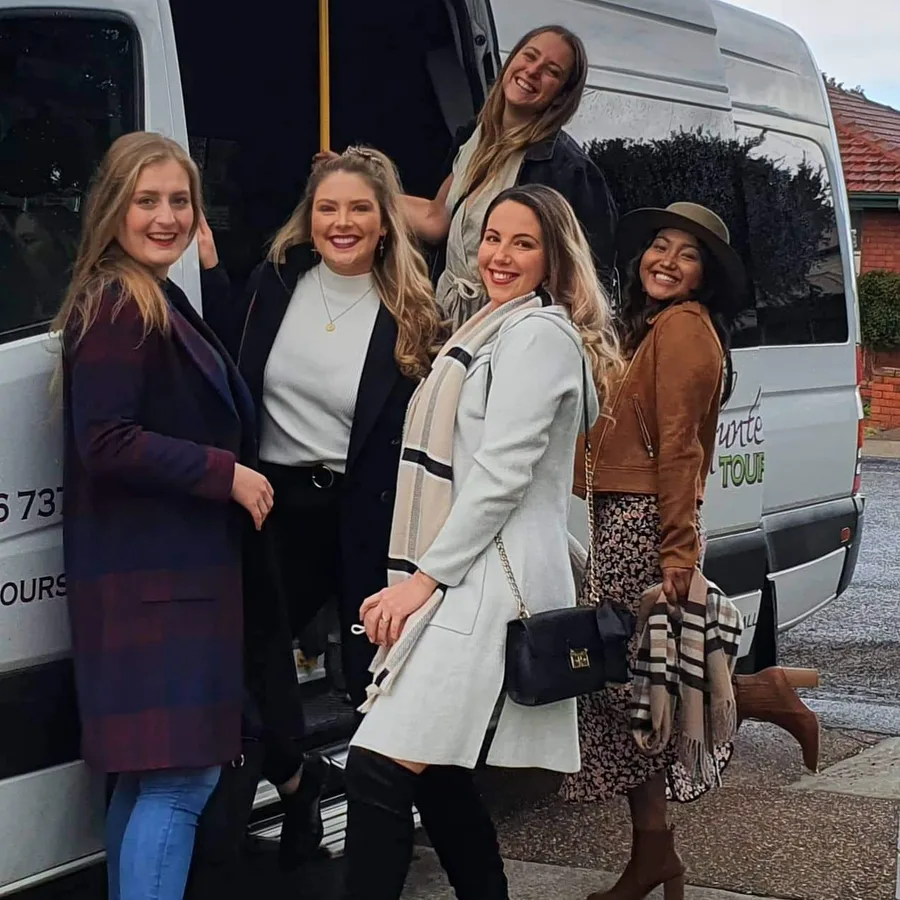 A big group of friends celebrates beside the tour bus