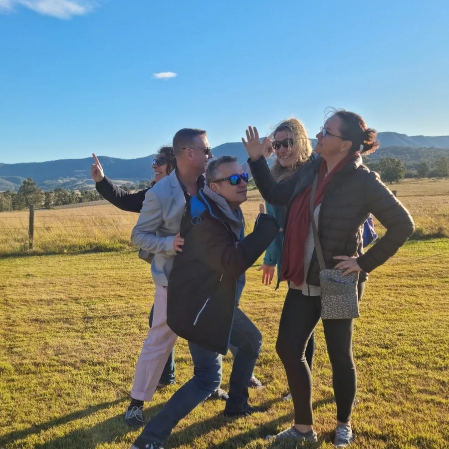 A group poses playfully in a grassy field at Harkham Wines
