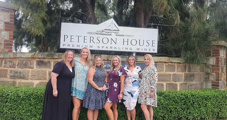 Six friends at the Peterson House sign