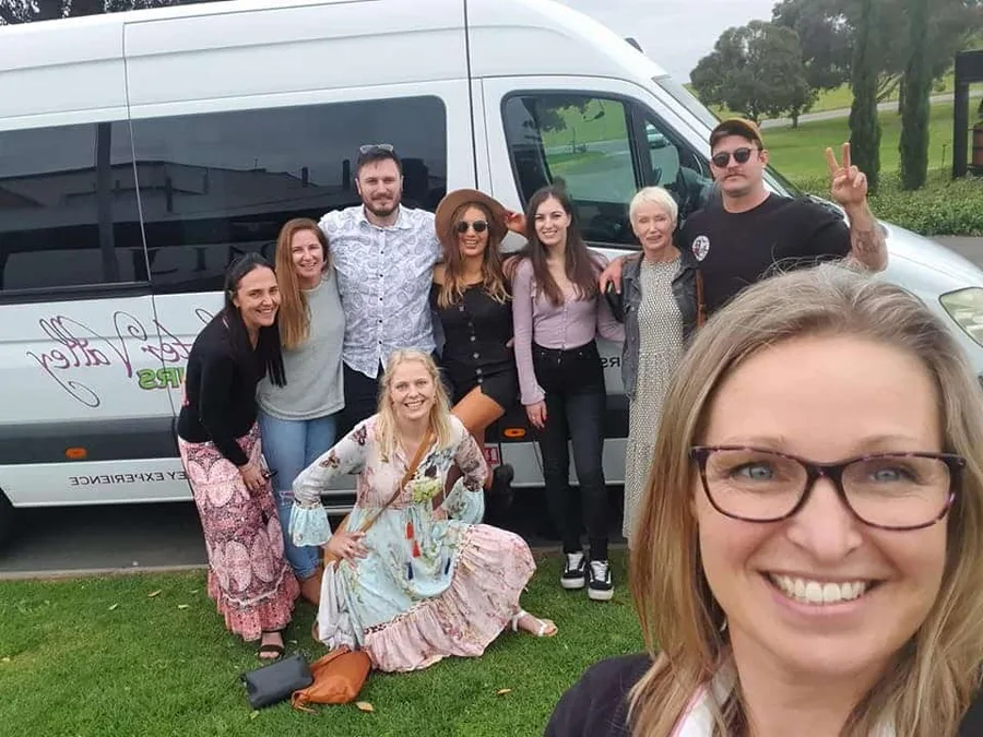 A small group takes a selfie in front of the HV Tours minibus
