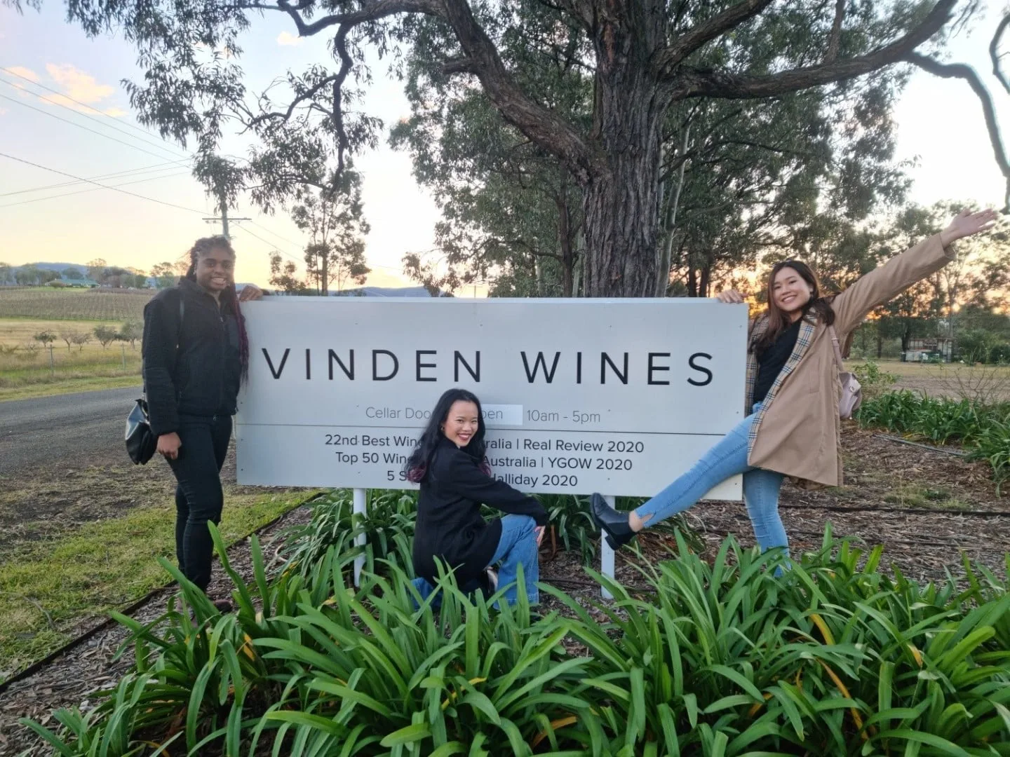 Guests at the Vinden Wines sign as the sun sets over the vines