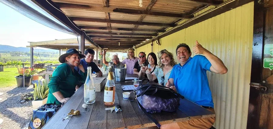 A tour group raises glasses around an outdoor tasting table