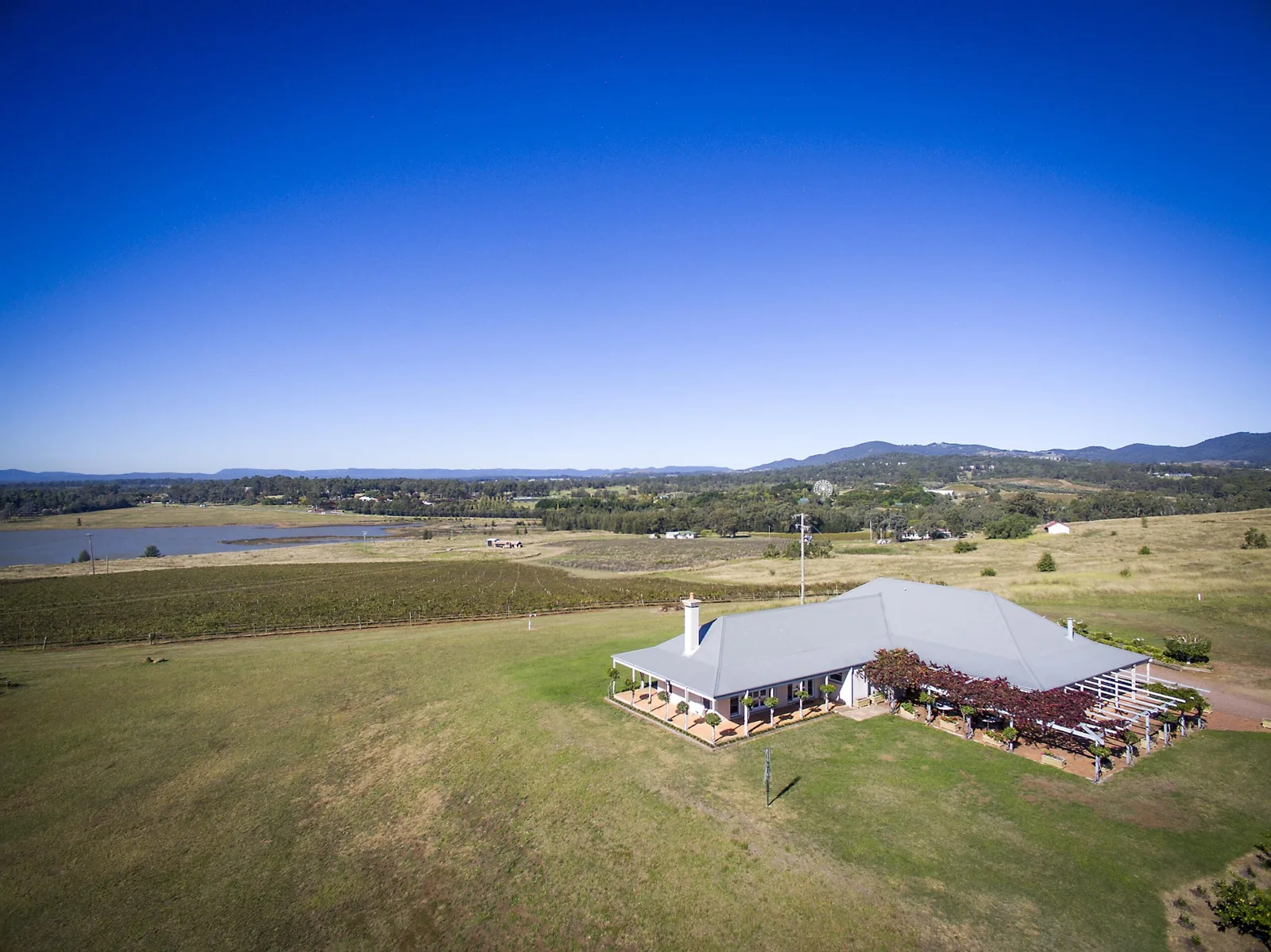 An aerial view of an estate house wrapped in vineyards and rolling hills