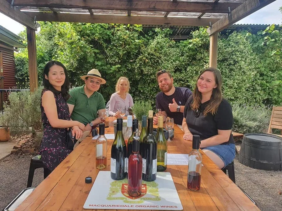 Friends settled in at an outdoor table with a few good bottles