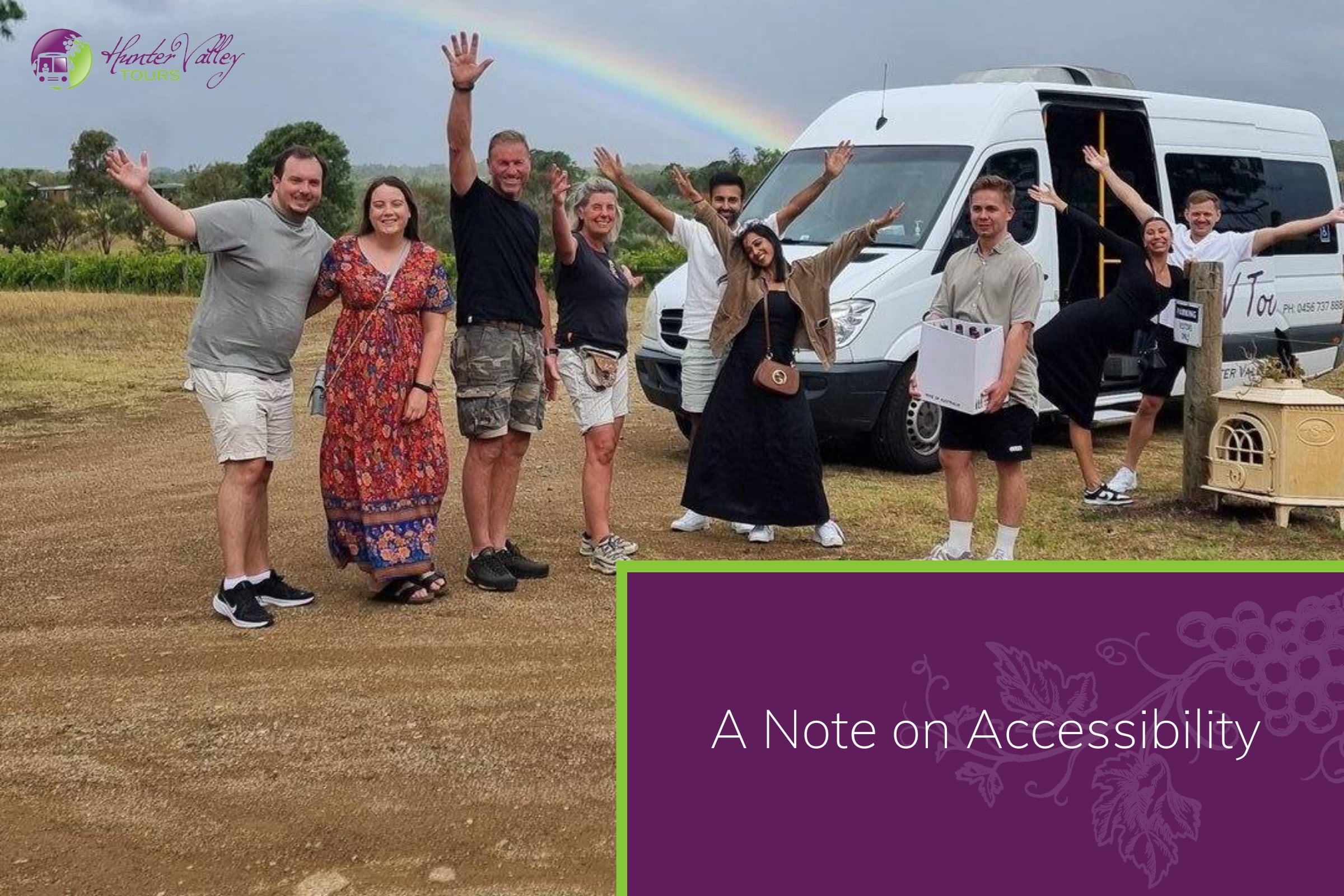 A happy tour group waving in front of a white tour minibus with a rainbow in the sky behind them
