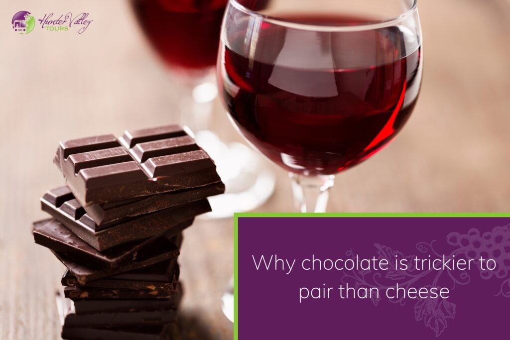 A stack of dark chocolate pieces next to a glass of red wine