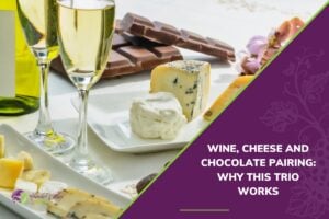 Two glasses of white wine set alongside blocks of cheese and a bar of milk chocolate